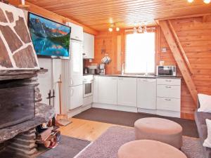 eine Küche mit weißen Schränken und einen TV in einer Hütte in der Unterkunft Holiday Home Lomasyväri 810 by Interhome in Nilsiä