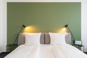 a bed with two white pillows and a green wall at Hotel Frechener Hof in Frechen
