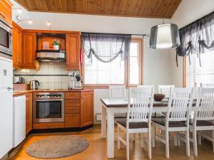 a kitchen with a wooden table and chairs and a table and a kitchen with at Holiday Home Tahkon klubitie 4 a by Interhome in Tahkovuori