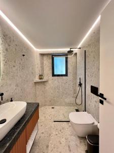 a bathroom with a white toilet and a sink at Becool Apartment in Porto Rafti