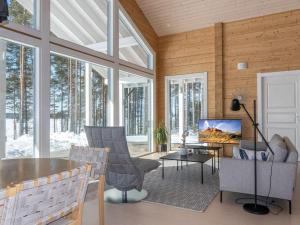 a living room with a table and chairs and a tv at Holiday Home Paloranta by Interhome in Kuhmo