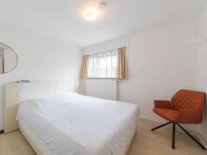 um quarto com uma cama branca e uma cadeira em Holiday Home Klemskerkestraat by Interhome em Bredene