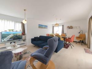 a living room with a blue couch and a tv at Holiday Home Klemskerkestraat by Interhome in Bredene