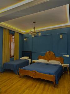 two beds in a room with blue walls at Promenade Hotel in Shkodër