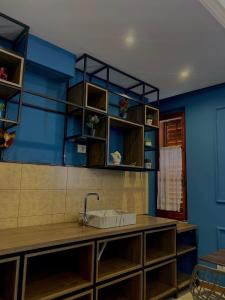 uma cozinha com um lavatório e uma parede azul em Promenade Hotel em Shkodër