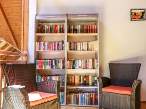 a book shelf filled with books next to two chairs at Holiday Home Draucamping-2 by Interhome in Sachsenburg