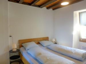 Duas camas num quarto com paredes brancas e uma janela em Apartment Tilleul by Interhome em Grimisuat