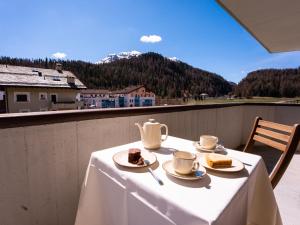 切勒里納的住宿－Apartment Chesa Palüdin 8 - Celerina by Interhome，阳台上的桌子上放着茶杯和蛋糕