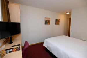 a hotel room with a bed and a flat screen tv at Meadow Farm Redditch by Marstons Inns in Redditch
