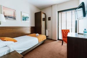 a bedroom with a bed and a desk and a chair at Hotel Willanova in Lublin