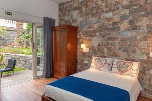 a bedroom with a brick wall and a bed at Quinta da Paz in Caniço +98 photos