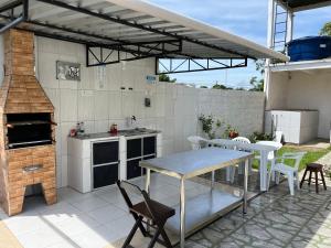 an outdoor kitchen with a table and chairs at Casa Boto Tucuxi 2 in Novo Airão