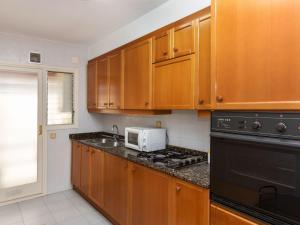 a kitchen with wooden cabinets and a stove top oven at Apartment Brumar by Interhome in Tossa de Mar
