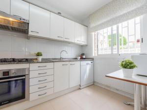 una cocina blanca con armarios blancos y fregadero en Holiday Home Canyadell by Interhome, en Torredembarra