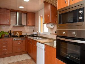 a kitchen with wooden cabinets and a stainless steel appliance at Holiday Home Can Alma by Interhome in Cunit