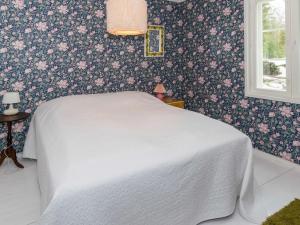 a bedroom with a white bed with floral wallpaper at Holiday Home Hiljanrinne by Interhome in Haminankylä