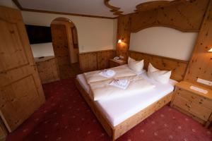 sypialnia z dużym białym łóżkiem i drewnianymi ścianami w obiekcie Panoramahotel Schwendbergerhof w mieście Hippach