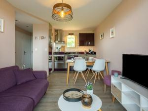 uma sala de estar com um sofá roxo e uma cozinha em Apartment Les Corniches du Mont Canisy by Interhome em Blonville-sur-Mer