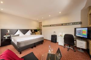 a bedroom with a bed and a desk and a television at Hotel Landgasthof König von Preussen in Marxzell