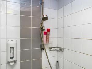 a shower with a hose in a white tiled bathroom at Holiday Home Point vale 3 by Interhome in Tahkovuori