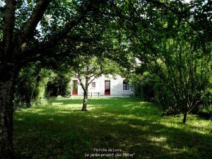 a white house in the middle of a yard with trees at Gîte Flottille de Loire in Chouzé-sur-Loire