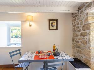 eine Küche mit einem Tisch, Stühlen und einer Steinmauer in der Unterkunft Holiday Home La Chaumière by Interhome in Névez