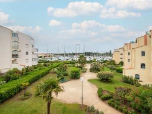 a view of a garden with a harbor in the background at Apartment Les Héliades-2 by Interhome in Cap d'Agde