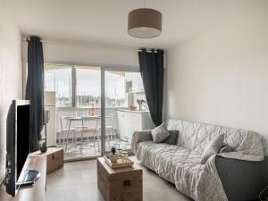 a living room with a couch and a tv and a kitchen at Apartment Les Héliades-2 by Interhome in Cap d'Agde