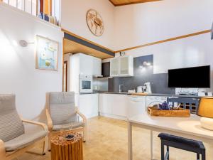eine Küche mit weißen Schränken sowie einem Tisch und Stühlen in der Unterkunft Holiday Home Le Canigounenc by Interhome in Sainte-Marie