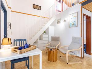 ein Wohnzimmer mit 2 Stühlen, einem Tisch und einer Treppe in der Unterkunft Holiday Home Le Canigounenc by Interhome in Sainte-Marie
