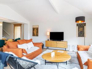 ein Wohnzimmer mit orangefarbenen Möbeln und einem TV in der Unterkunft Holiday Home Maison les Dunes by Interhome in Saint-Lunaire
