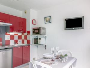 kuchnia z czerwonymi szafkami i stołem z krzesłami w obiekcie Apartment Port Plage 2 by Interhome w mieście Le Barcarès