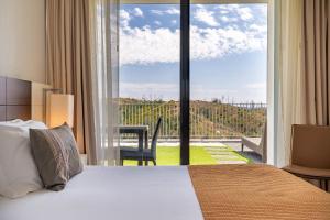 a hotel room with a bed and a large window at Monchique Resort & Spa in Monchique