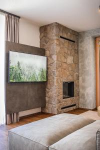 a bedroom with a stone wall with a flat screen tv at Apartmany Furkotka - Ovruč in Štrbské Pleso