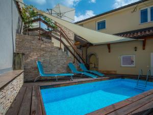 basen z 2 niebieskimi krzesłami obok domu w obiekcie Holiday Home Veli by Interhome w mieście Veli Brgud