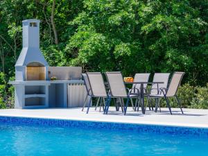 a group of chairs and a barbecue next to a swimming pool at Apartment Eroa by Interhome in Žminj