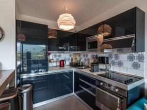 une cuisine avec des placards noirs et un mur en carrelage bleu dans l'établissement Apartment Résidence Cita Di Sali 12 by Interhome, à Porto-Vecchio