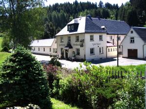 ein großes weißes Gebäude mit einem Haus und Bäumen in der Unterkunft Gasthaus Stollmühle in Stützengrün