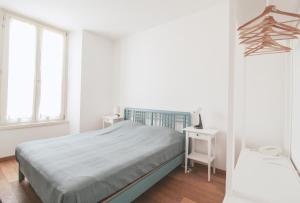 a white bedroom with a bed and a desk at Appartamento La Perla del Lago in Dongo