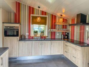 eine große Küche mit Holzschränken und schwarzen Arbeitsplatten in der Unterkunft Holiday Home Wiringherlant-11 by Interhome in Hippolytushoef