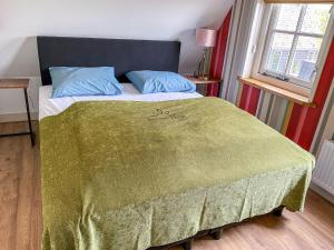 ein Schlafzimmer mit einem Bett mit einer grünen Decke darauf in der Unterkunft Holiday Home Wiringherlant-11 by Interhome in Hippolytushoef