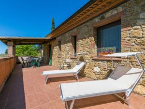 a patio with two lounge chairs and a stone building at Apartment Tramontana by Interhome in Bibbona