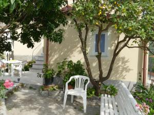 a white chair sitting in front of a house with an orange tree at Holiday Home Ca'Mea by Interhome in Chiusanico