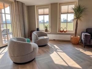un soggiorno con due sedie e finestre di Holiday Home Wiringherlant-12 by Interhome a Hippolytushoef