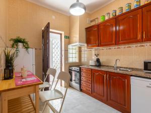 een keuken met houten kasten en een tafel en stoelen bij Holiday Home Magnolia by Interhome in Olhão