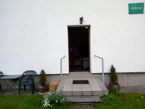 une porte d'entrée d'un bâtiment blanc avec une table et des chaises dans l'établissement ANIA, à Kamienna Góra
