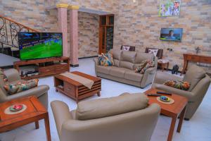 a living room with couches and a flat screen tv at Fort Heights Homestay in Fort Portal