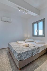 a white bedroom with a large bed and a window at Sand house Antiparos in Antiparos