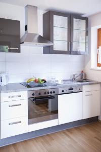 a kitchen with white cabinets and a stove top oven at Ferienwohnung Rust in Fendels