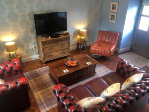 a living room with leather furniture and a flat screen tv at Cauldholm in Moffat